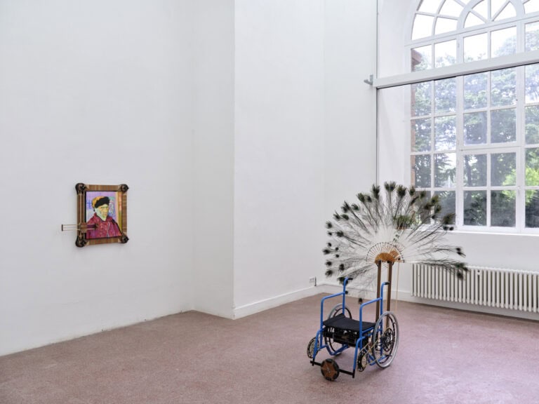 Foto: Ansicht eines Raumes mit weißen Wänden, rötlichem, gekachelten Boden und einem großen Fenster. An einer Wand des Raumes befindet sich ein Objekt, im Raum steht ein weiteres.