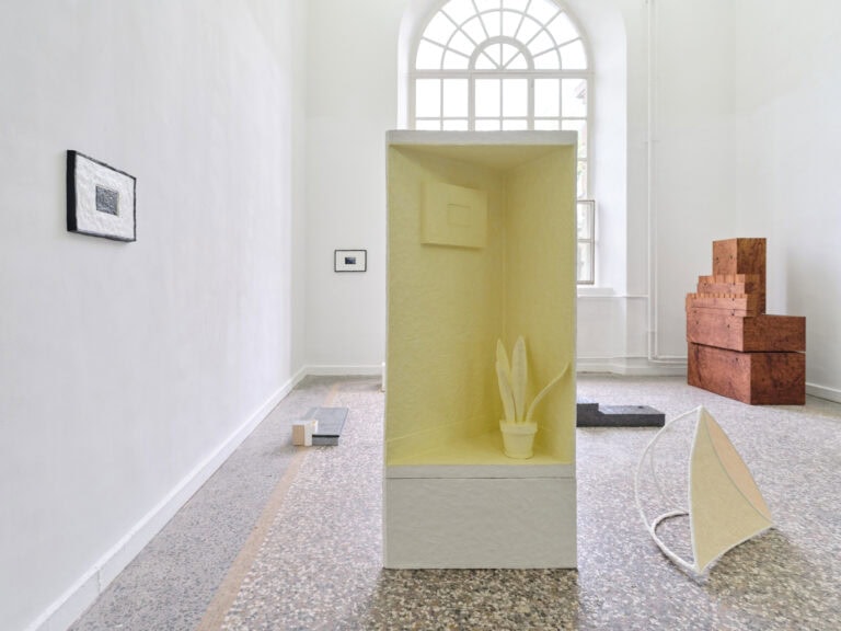 Foto: Ansicht eines Raumes mit weißen Wänden, mehrfarbigem Steinboden und einem großen Bogenfenster. Im Raum verteilt befinden sich mehrere Objekte, die auf dem Boden stehen. An den Wänden hängen weitere Objekte.