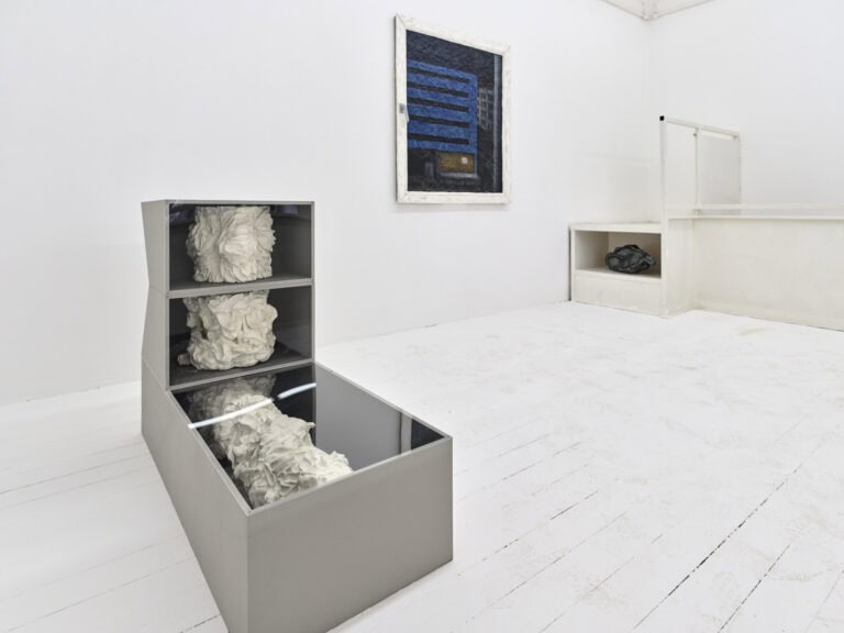 Foto: Ansicht eines Raumes mit weißen Wänden und weißem Dielenboden. Im Raum verteilt, auf dem Boden und an der Wand, befinden sich unterschiedliche Schränke und Objekte.