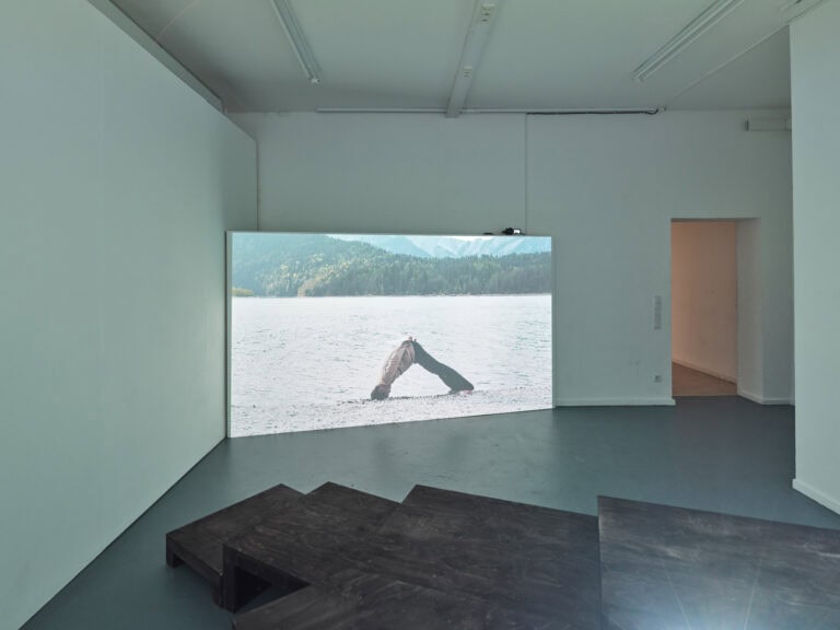Foto: Ansicht eines Raumes mit weißen Wänden und grauem Boden. In einer Ecke des Raumes ist ein großer Screen aufgestellt. Vor den Screen befindet sich eine gestufte Konstruktion.