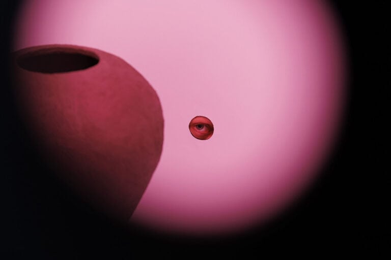 Foto: Ansicht einer Fläche, die in rotes Licht getaucht ist. Darauf eine Form mit Auge in der Mitte.
